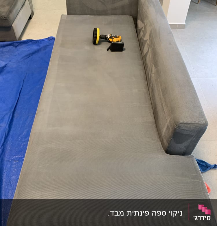 ספה אפורה עם מברשת ניקוי חשמלית על בד כחול